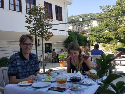 a man and woman sitting at a table with plates of food at Hotel Gjirokastra in Gjirokastër