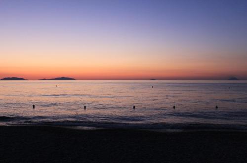 a group of people in the ocean at sunset at Karma Resort in Venetico