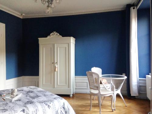 サント・マリー・オー・ミーヌにあるB&B La Clé d'Alsaceの青い壁のベッドルーム(テーブル、椅子付)