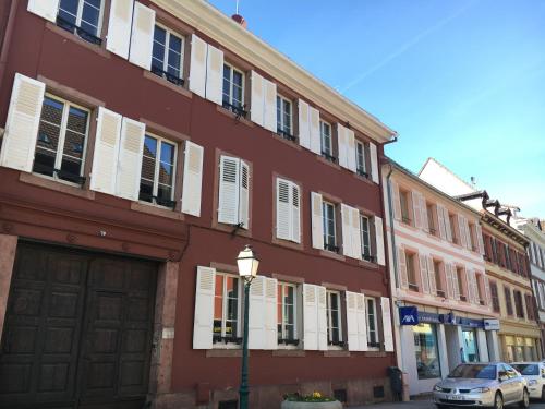 un bâtiment rouge avec des fenêtres blanches à volets et une lumière de rue dans l'établissement B&B La Clé d'Alsace, à Sainte-Marie-aux-Mines