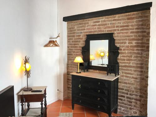 a black dresser with a mirror on a brick wall at Pátio das Andorinhas in Ferreira do Alentejo