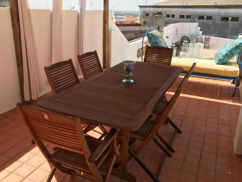 a wooden table with chairs and a glass on a balcony at Pátio das Andorinhas in Ferreira do Alentejo