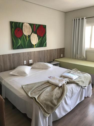 Un dormitorio con una cama blanca con una manta. en Hotel Pousada Mato Grosso en Campo Grande