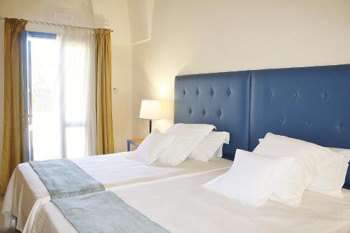 a large bed with a blue headboard and white pillows at Antica Masseria Torre Mozza in Torre Santa Susanna