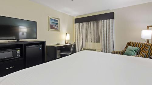 a hotel room with a bed and a tv at Best Western Mayport Inn and Suites in Atlantic Beach