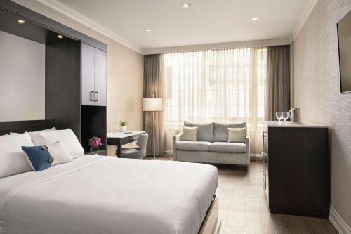 a hotel room with a large bed and a chair at Georgian Court Hotel, WorldHotels Elite in Vancouver