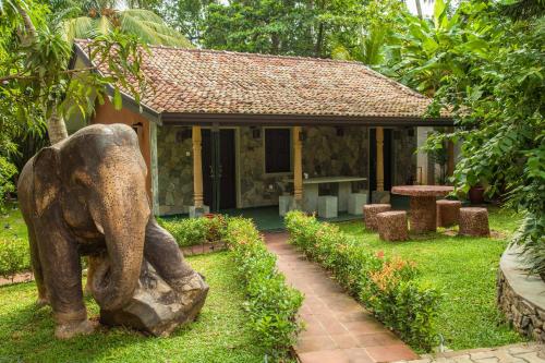 a statue of an elephant standing in front of a house at Villa Pinnawala in Pinnawala