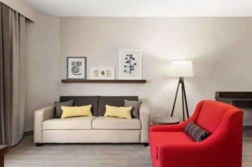 a living room with a couch and a red chair at Country Inn & Suites by Radisson, Shreveport-Airport, LA in Shreveport