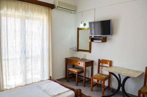 a room with a bed and a desk and a tv at Kalypso in Agia Galini