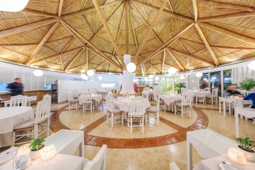 a dining room with white tables and chairs and a large ceiling at Encosta Do Lago Resort Club in Quinta do Lago