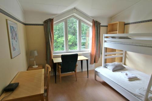 a bedroom with a bunk bed and a desk and a table at STF Sigtuna Vandrarhem in Sigtuna