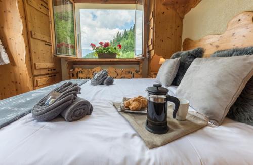 a bed with a coffee mug and a plate of food on it at Chalet Bluebell in Les Gets