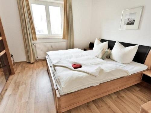 ein großes weißes Bett mit einer roten Rose drauf in der Unterkunft moderne Ferienwohnung (App.30) - Ostseeurlaub in Timmendorfer Strand