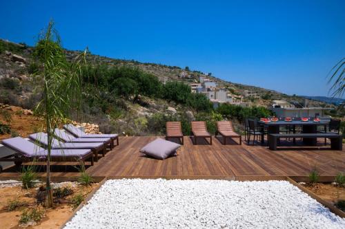 a wooden deck with chairs and a table on a hill at Seametry Apartments in Souda