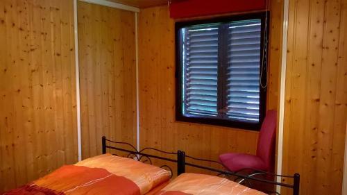 a bedroom with a bed and a window and a chair at Ferienhaus-Maxen in Müglitztal