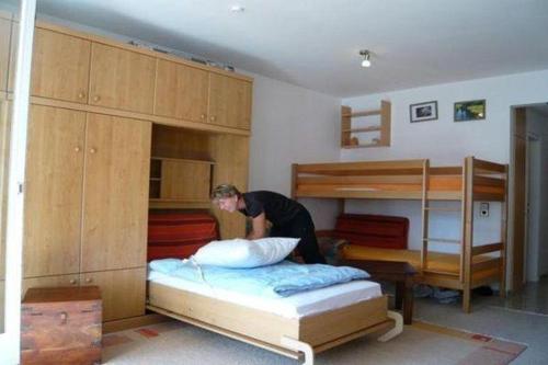 a person making a bed in a room with bunk beds at Falkenberg-Wohnung-201 in Oberstdorf