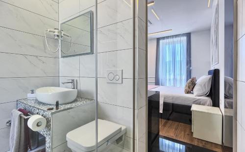 a bathroom with a sink and a toilet and a bed at Mincheta - Luxury Rooms in Primošten