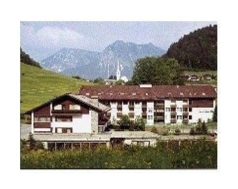 a building in a field with mountains in the background at Sport-Alpin-Wohnung-9 in Oberstdorf
