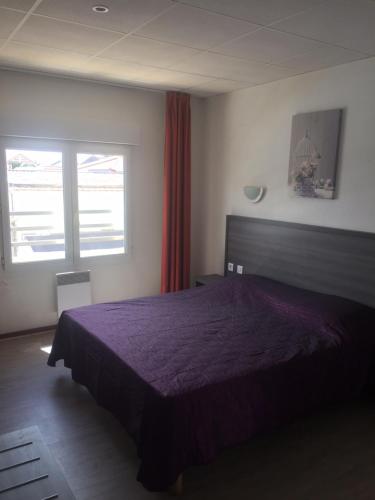 una camera con letto viola e finestra di Hôtel Le Neptune a Soulac-sur-Mer