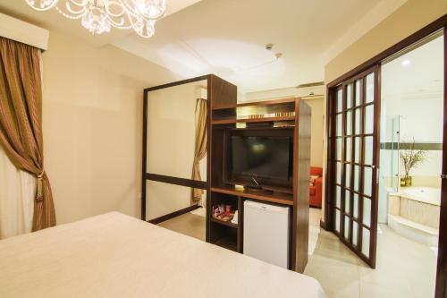 a room with a television and a living room at JR Hotel in Presidente Prudente