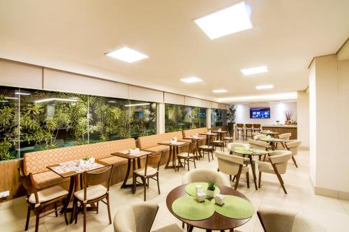 a restaurant with tables and chairs and windows at JR Hotel in Presidente Prudente