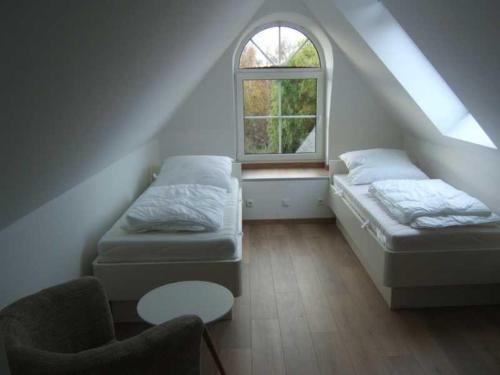 ツィングストにあるPiratennest-2のベッド2台と窓が備わる屋根裏部屋です。