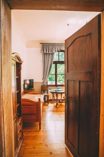 an open door to a bedroom with a bed and a table at Pałac Poraj in Wicko