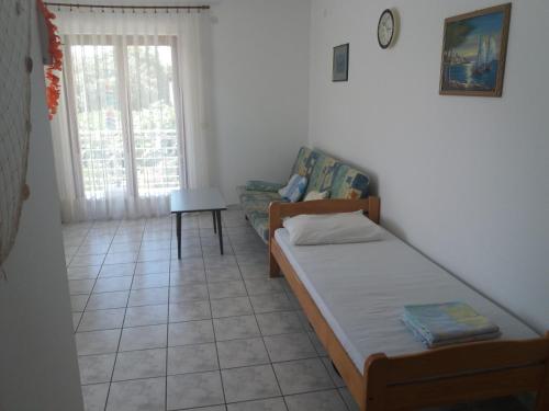 um pequeno quarto com uma cama e um sofá em Apartment Lokvice em Novalja