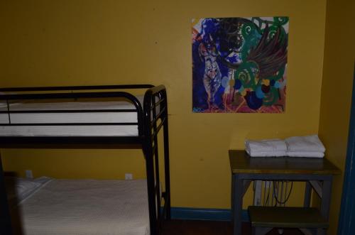 a bedroom with a bunk bed and a table and a painting at India House Hostel in New Orleans