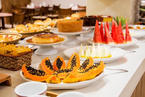 a buffet filled with different types of desserts on plates at JR Hotel in Presidente Prudente