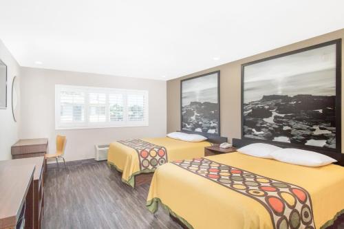 ein Hotelzimmer mit 2 Betten und 2 Fenstern in der Unterkunft Super 8 by Wyndham National City Chula Vista in National City