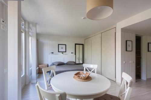 a white dining room with a white table and chairs at Preilos vasara in Preila