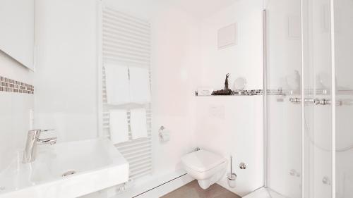a white bathroom with a toilet and a shower at Anno 1433 Hotel Lüneburg in Lüneburg