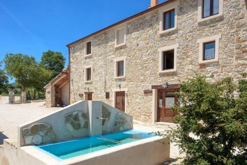 a stone house with a swimming pool in front of a building at Agriturismo Dai Du Bourdei in Frontino