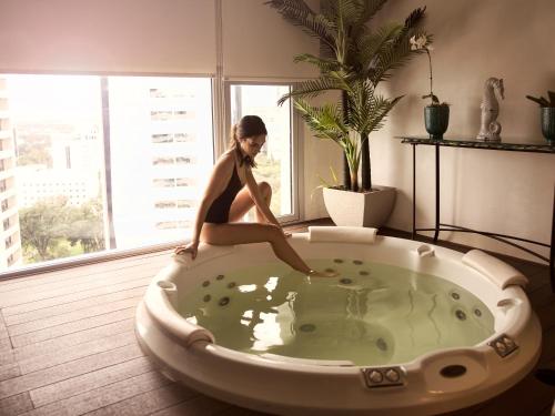 a woman sitting in a bath tub in a room at Dazzler by Wyndham Asuncion in Asuncion