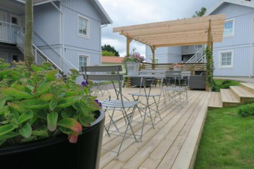 a deck with chairs and tables and a pergola at Easy Livin' Apartment Hotel in Växjö