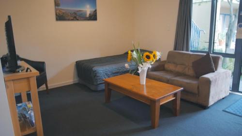a living room with a couch and a table with flowers at Sherborne Motor Lodge in Christchurch