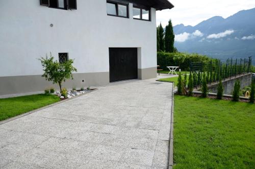 a driveway leading to a white house with a black door at Al Trifoglio in Campodenno