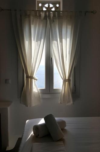 a bedroom with a window with white curtains at Avissalou Apartments in Agios Romanos