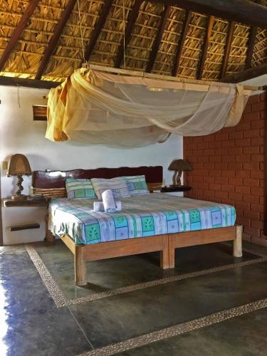 Bett in einem Zimmer mit Moskitonetz in der Unterkunft Cabañas Las 3 Marias in San Agustinillo