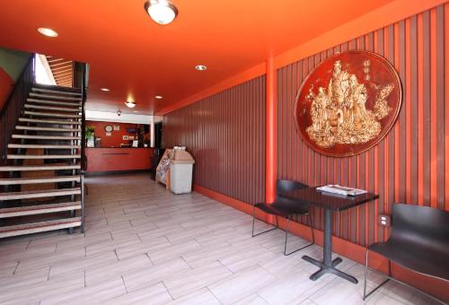 a lobby with orange walls and a table and stairs at Royal Pagoda Motel Dodger Stadium in Los Angeles