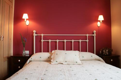 a bedroom with a white bed with a red wall at Apartamentos Rurales La Carbayala in Oviñana