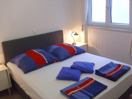 a bed with blue and red pillows on it at Open Hus in Krvavica