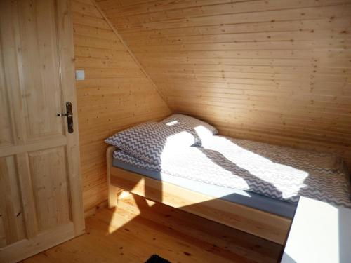 a small room with a bed in a wooden cabin at Cztery Pory Roku in Trzęsacz