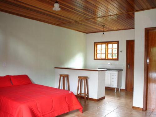 a bedroom with a red bed and a counter at Chalé Recanto do Sossego in Gonçalves