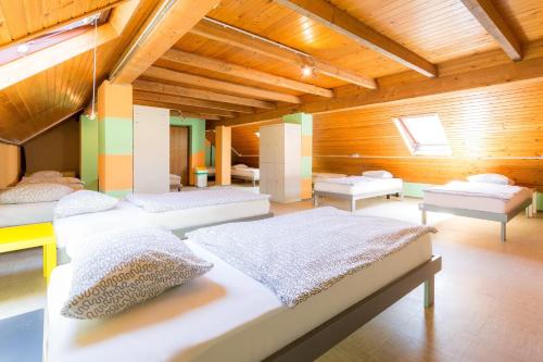 una camera con 4 letti in una stanza con soffitti in legno di 1A Adventure Hostel a Lesce