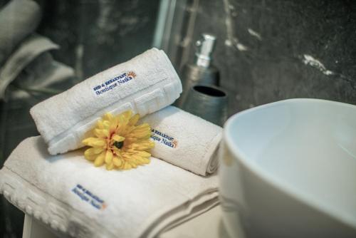 a bathroom with towels and a flower on top of a toilet at Hotel Boutique Natka in Rovinj