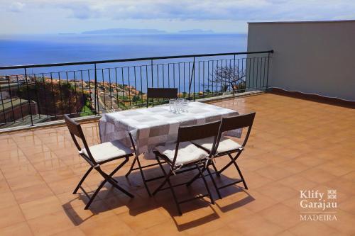 a table and chairs on a balcony with the ocean at Klify Garajau in Caniço