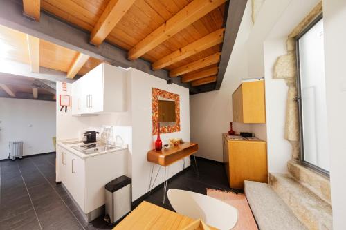 uma cozinha com armários brancos e um tecto de madeira em Antiga Casa da Burra em Viseu