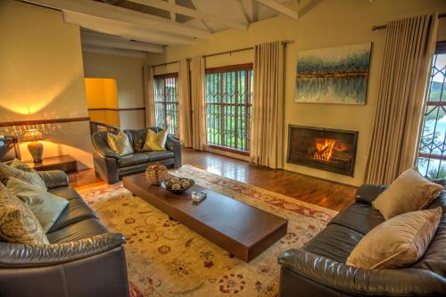 a living room with leather furniture and a fireplace at Pavetta Country House in Magoebaskloof